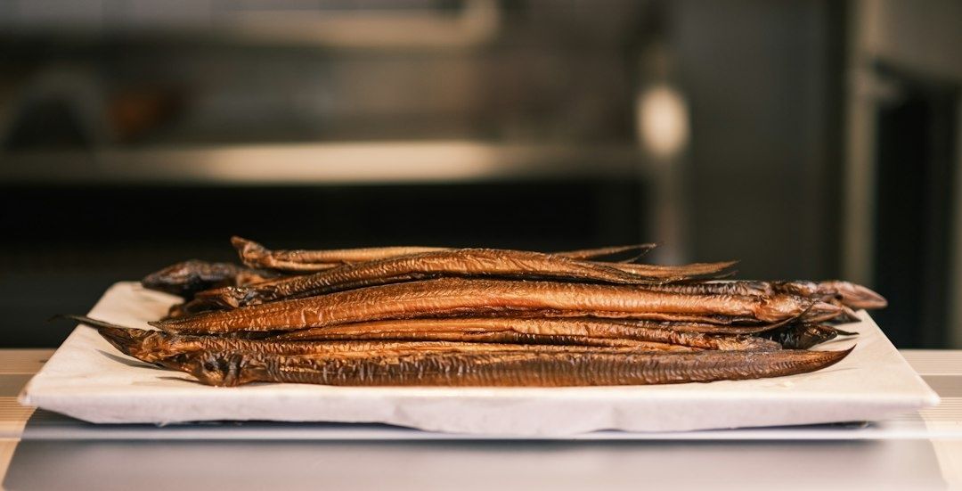 En hög med rökt småfisk på ett vitt fat, serverad på ett bord